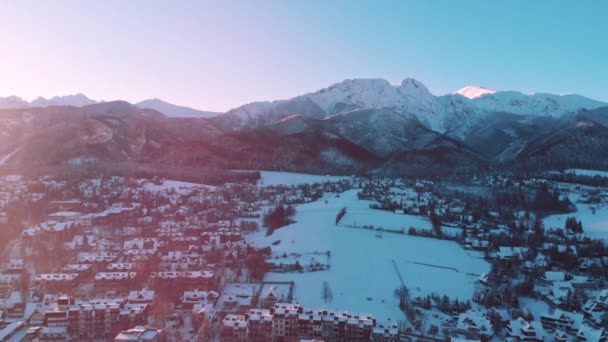 Impresionante amanecer sobre el bosque siempreverde durante la caída de nieve y la pequeña ciudad Zakopane, Polonia — Vídeo de stock