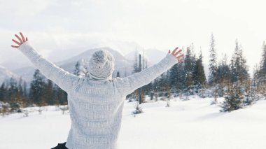 Genç kadın karı seyrediyor ve ellerini dağa kaldırıyor.