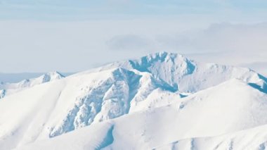 Kışın karlı dağlarda gündüz vakti bulutlu mavi gökyüzü