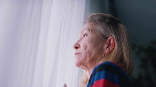 Portrait de femme âgée solitaire regardant par la fenêtre — Video