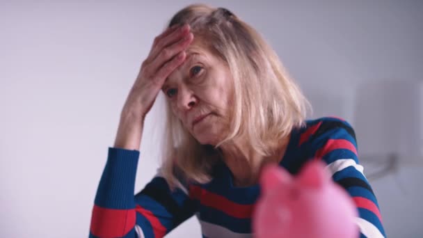 Besorgte alte Frau vor leerem Sparschwein. Geringe Rente — Stockvideo