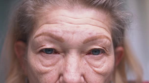 Gros plan sur les yeux bleus d'une femme âgée à la peau ridée. Dépression à la vieillesse — Video