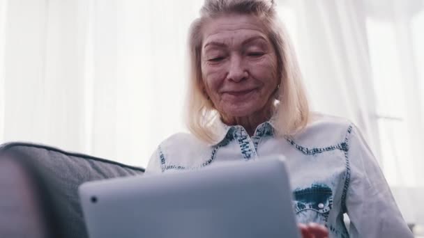 ビデオ通話にラップトップを使用している高齢女性。彼女の家族に心を送る — ストック動画
