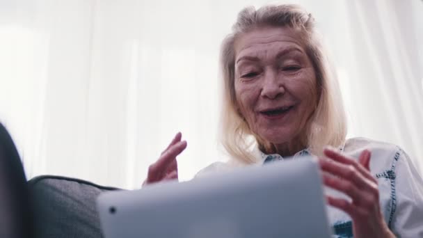 Oudere vrouw die laptop gebruikt om haar familie te zien. Zwaaien naar de camera — Stockvideo
