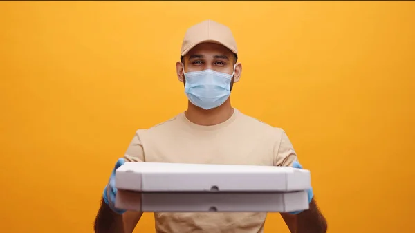 El repartidor sonríe mientras sostiene cajas de pizza. Pedir alimentos durante la pandemia — Foto de Stock