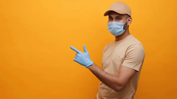 Joven con máscara médica y guantes señalando con el dedo el espacio vacío — Foto de Stock