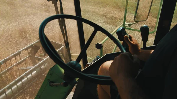 Vue de l'intérieur d'une moissonneuse batteuse. Un agriculteur manipulant le volant travaillant sur le terrain — Photo