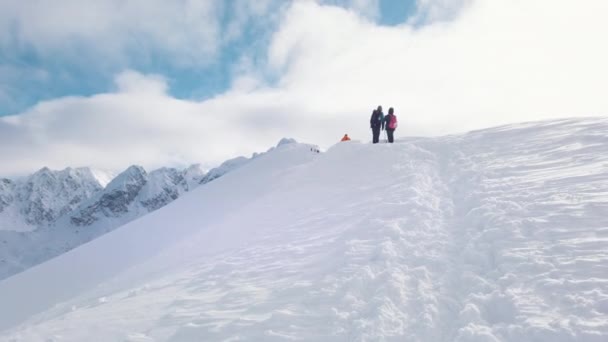 Visão traseira de dois montanhistas em uma montanha coberta de neve contra o céu azul nublado — Vídeo de Stock