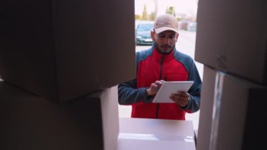 Paketi teslim ederken tablet kullanan genç Hintli kurye.