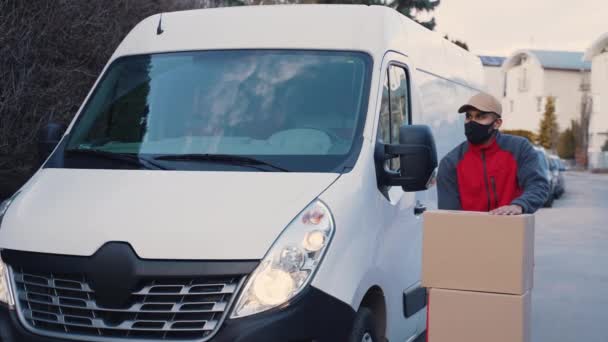 Mensajero entregando paquetes durante covid19, Hombre usando máscara mientras lleva cajas — Vídeos de Stock