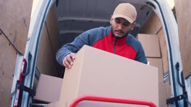 Jonge indiaanse man die een tablet gebruikt om de bestelling te controleren. Laadwagen met kartonnen dozen — Stockvideo
