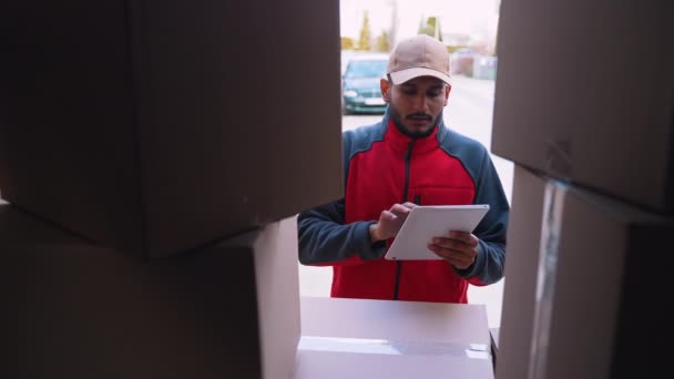 Jonge indiase man koerier met behulp van tablet tijdens het leveren van pakket — Stockvideo
