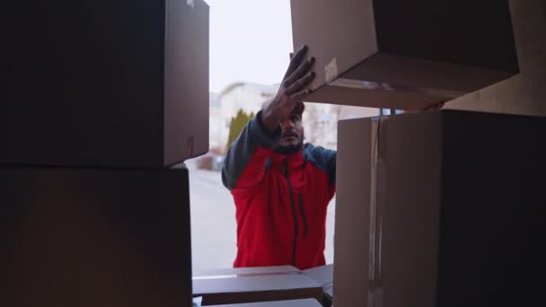 Young courier unloading parcels from the truck — Stock Video