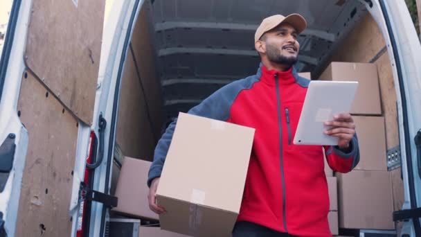 Joven mensajero indio hombre usando tableta mientras entrega paquete — Vídeos de Stock