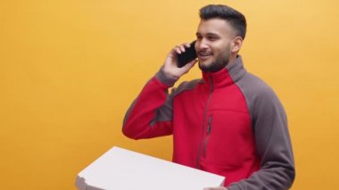 Genç Hint kuryesi pizza teslimatı yapıyor. Müşteriyle telefonda konuşuyorum.