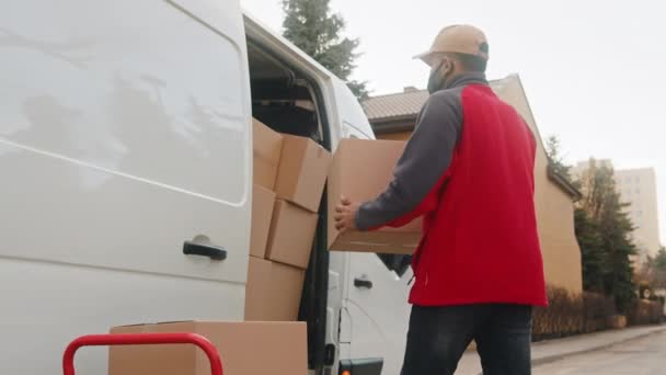 Молодой человек в маске погрузки фургона с картонными коробками — стоковое видео