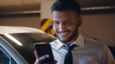 Gülümseyen iş adamı yeraltı garajında video görüşmesi yapıyor.