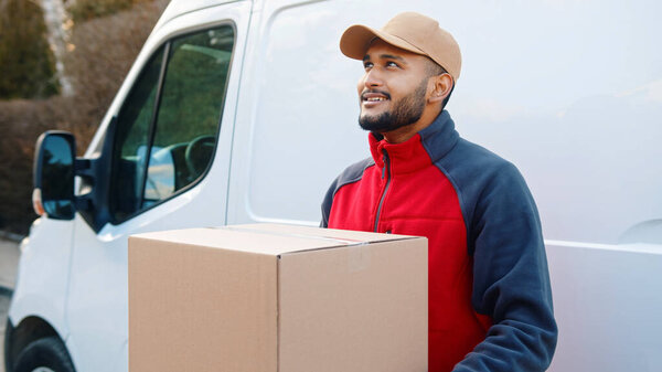 Smiling bearded delivery man wearing beige cap looking away