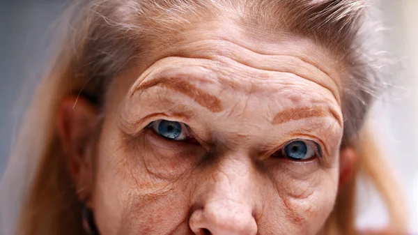 Close-up em olhos azuis de uma mulher idosa com pele enrugada. Depressão na velhice — Fotografia de Stock