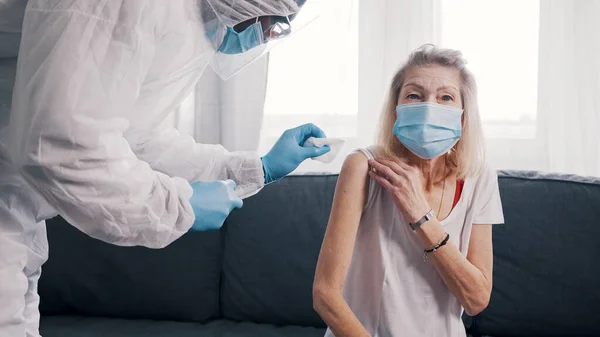Doktor maske takan yaşlı kadına Covid aşısı yapıyor. — Stok fotoğraf