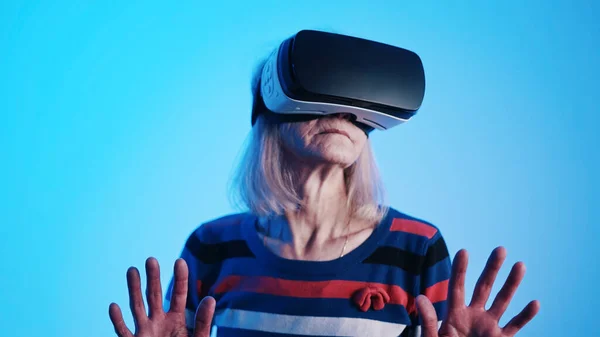 Старая белая женщина в наушниках VR, касающихся воздуха — стоковое фото