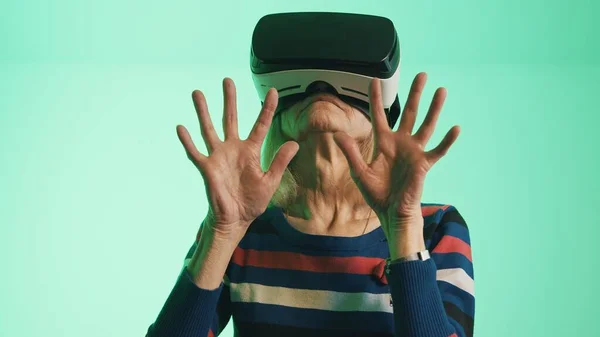 Старая белая женщина в наушниках VR, касающихся воздуха — стоковое фото