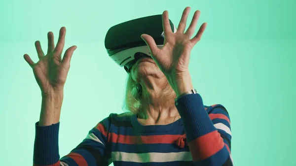 Elderly woman with Virtual Reality glasses touching the air — Stock Photo, Image