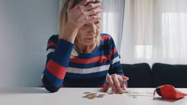 Zavallı yaşlı kadın masada bozuk para sayıyor. Finansal sorunları olan umutsuz yaşlı bir kadın.