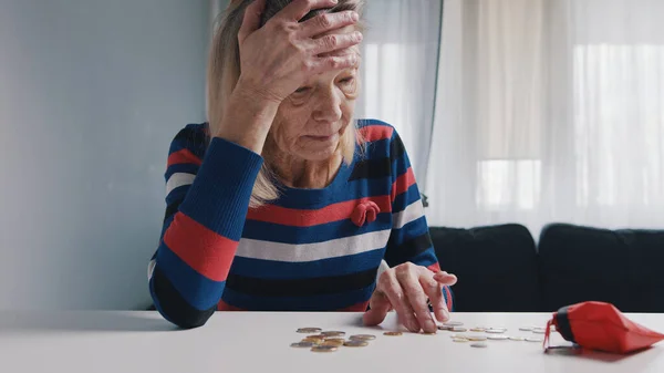 Бедная старуха считает монеты на столе. Безнадежная пожилая женщина с финансовыми проблемами — стоковое фото