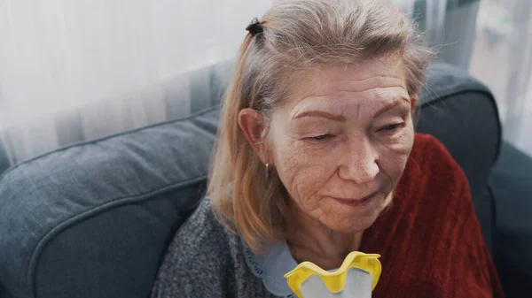 Пожилая женщина использует кислородную маску у себя дома — стоковое фото