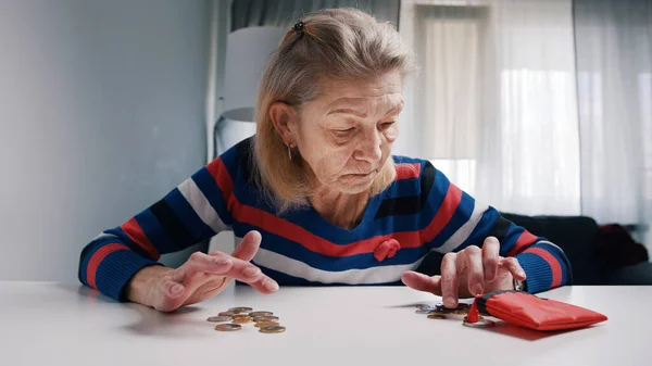 Бедная старуха считает монеты на столе. Низкая пенсия и недостаток средств — стоковое фото