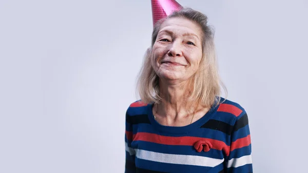 Portrait of an old woman with party hat isolated on gray background — Stock Photo, Image