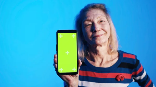 Vieja mujer caucásica mostrando teléfono inteligente con pantalla verde — Foto de Stock