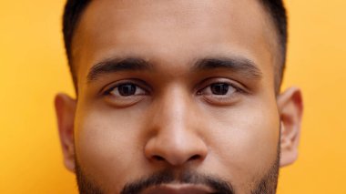 Orta yaşlı erkek yüzü turuncu arka planda kameraya bakıyor.