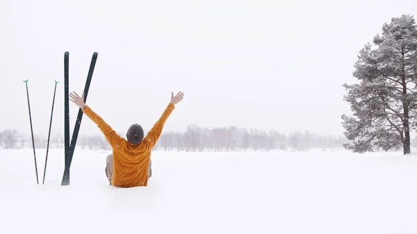 Osoba siedząca w śniegu z ramionami wyciągniętymi do góry — Zdjęcie stockowe
