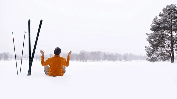 Człowiek siedzący na śnieżnej ziemi i wykonujący gest — Zdjęcie stockowe