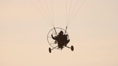 Paramotor trike paraşüt altında kameraya doğru uçuyor.