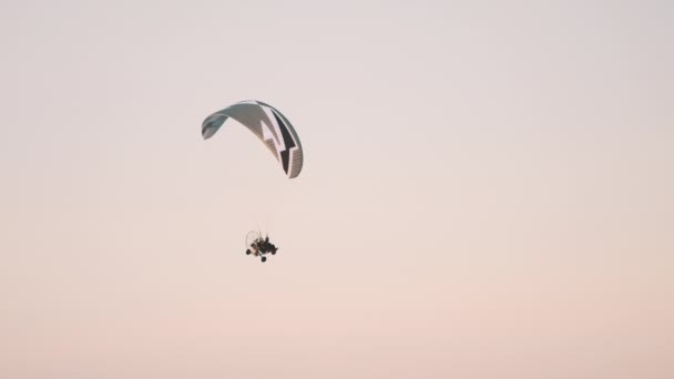 Paramotor simán fordul, miközben repül ellen naplemente ég — Stock videók