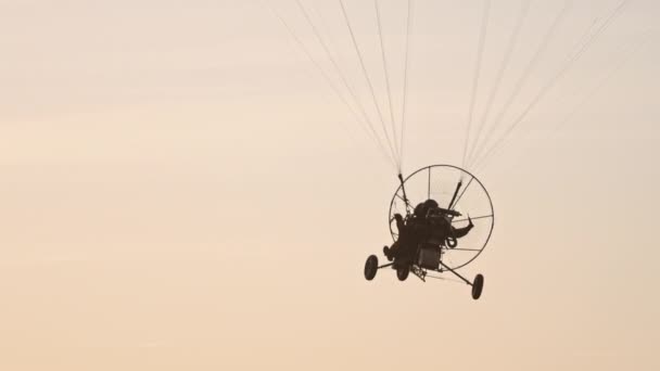 Paraşüt koltuğu paraşütün altında asılı, gün batımına doğru uçuyor. — Stok video