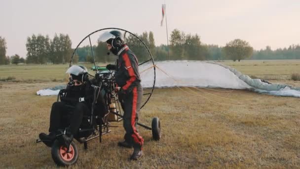 Instructor haciendo la preparación para el inicio del paramotor con el cliente — Vídeos de Stock