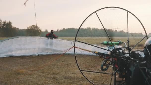 Man inspecting parachute while is filled by air from running propeller — Stock Video