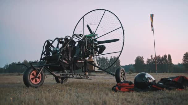 Paramotor trike στέκεται στο γρασίδι, δίπλα σε ρούχα και εργαλεία ασφαλείας — Αρχείο Βίντεο