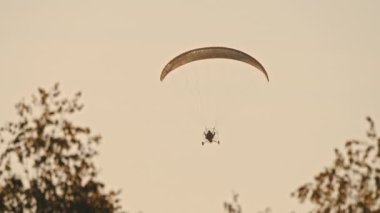 Paramotor gün batımına karşı havada uçuyor.