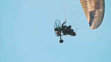 Paramotor trike havada paraşütün altında asılı.
