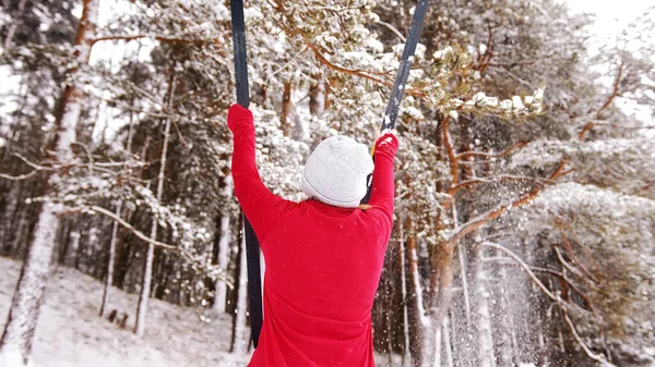 Kobieta trzymająca narty w powietrzu i wyciągnięte ręce przed sosnowym lasem pokrytym śniegiem — Zdjęcie stockowe