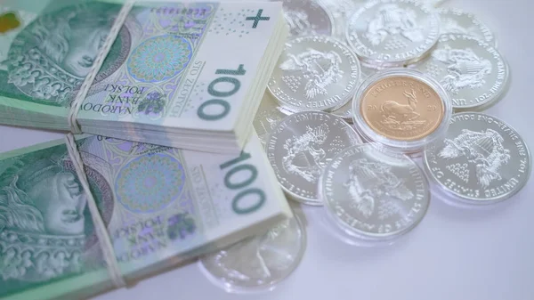 Ganancias de capital. Pila de monedas de inversión de plata y billetes de 100 zloty — Foto de Stock