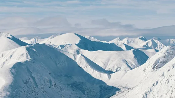 Snowy landscape in the winter season. Snow-covered mountains against the cloudy sky