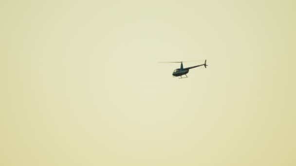 Hélicoptère Voler contre le ciel blanc clair en arrière-plan pendant la journée. — Video