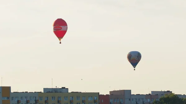 Két színes hőlégballon a lakások felett a tiszta fehér ég ellen — Stock Fotó