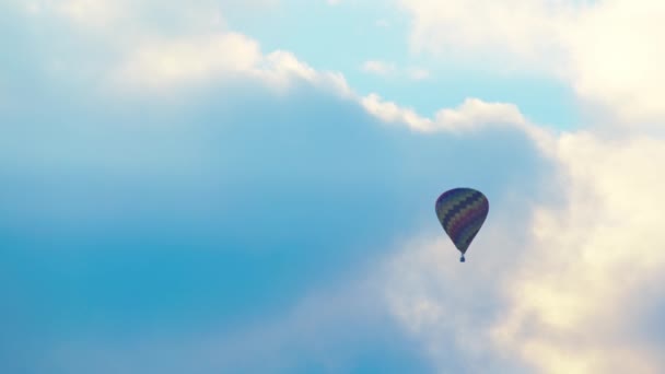 Вид с воздуха на разноцветные воздушные шары, летящие на фоне живописного облачного голубого неба — стоковое видео